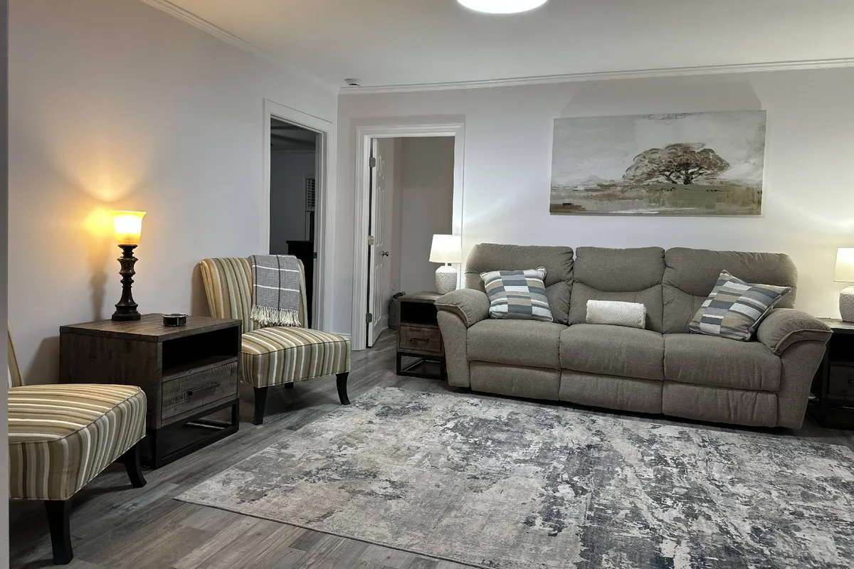 A welcoming corner of the living room, featuring a soft sofa, tasteful wall art, and side tables with lamps that create an intimate ambiance. The setting is cozy and perfect for relaxed conversations, reading, or unwinding after a day’s adventures.