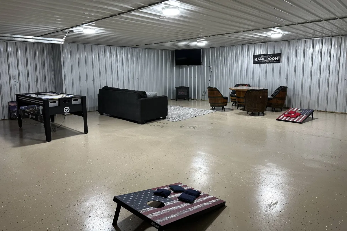 A vibrant social space with a central air hockey table, plush sofa, large television, and a generous dining table in the background. The room is brightly lit, fostering a fun and welcoming atmosphere ideal for group activities and game nights.