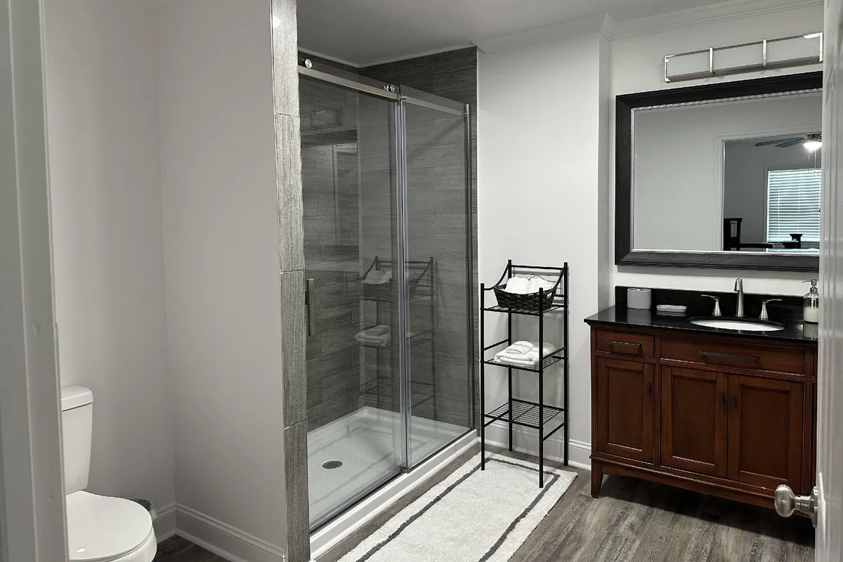 A modern bathroom with a glass shower enclosure, dark wood vanity, large mirror, and neatly arranged towels. The space feels serene, clean, and perfect for self-care routines.